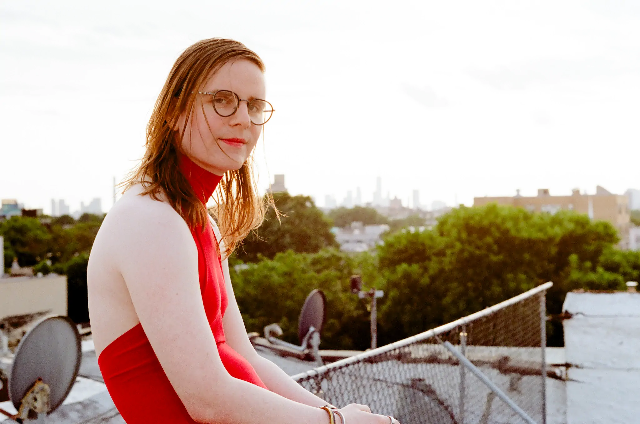 mb bischoff. a white trans woman in a red dress on a roof